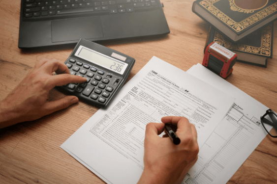 Pessoa calculando a tabela regressiva previdência privada, com um papel, calculadora e caneta